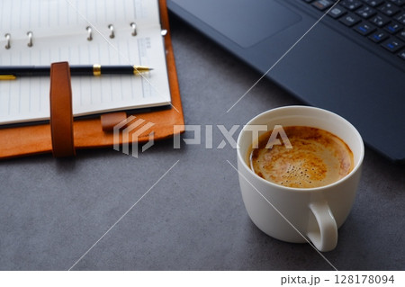 淹れたての美味しいコーヒーを飲みながら、ノートパソコンとシステム手帳でデスクワークをしているイメージ 淹れたての美味しいコーヒーを飲みながら、ノートパソコンとシステム手帳でデスクワークをしているイメージ 128178094
