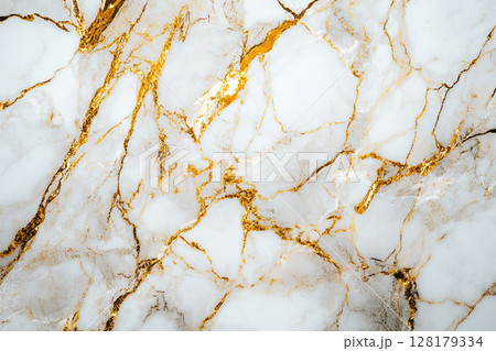 A luxurious white marble surface intricately veined with striking gold and subtle brown patterns, creating an elegant and opulent abstract background. 128179334