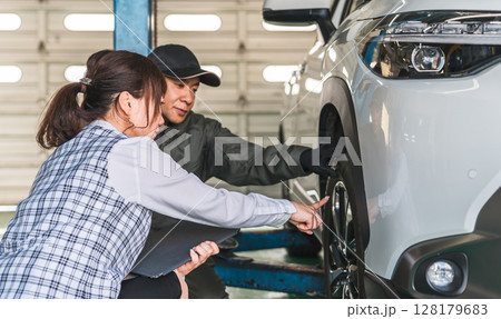 自動車の前で会話する自動車整備士の男性と事務服姿の女性フロント,事務員 128179683