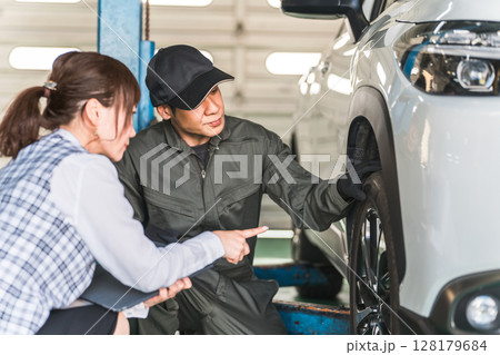 自動車の前で会話する自動車整備士の男性と事務服姿の女性フロント,事務員 128179684