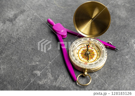 Closeup view of navigational compass and pink compasses on a black background. Travel guidance equipment Closeup view of navigational compass and pink compasses on a black background. Travel guidance equipment 128183126