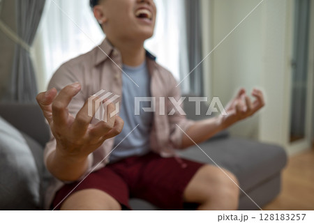 Indonesian southeast asian man in the living room with mental health, fatigue, and sad problems. Faced with depression, frustration, tiredness, headaches, and stress. Healthcare concept 128183257