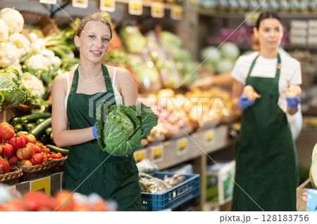 While working in shop, girl shop assistant add cabbage in showcase 128183756