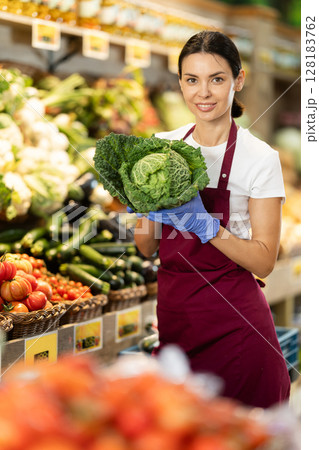 While working in shop, girl shop assistant add cabbage in showcase While working in shop, girl shop assistant add cabbage in showcase 128183762