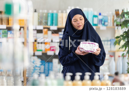 Young Muslim woman in summer clothes choosing feminine pads in chemistry 128183889