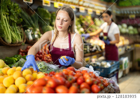 Saleswoman laying out peaches on the counter Saleswoman laying out peaches on the counter 128183935