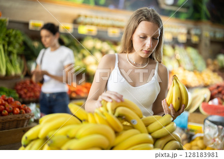 Young woman choosing bananas at vegetable shop 128183981