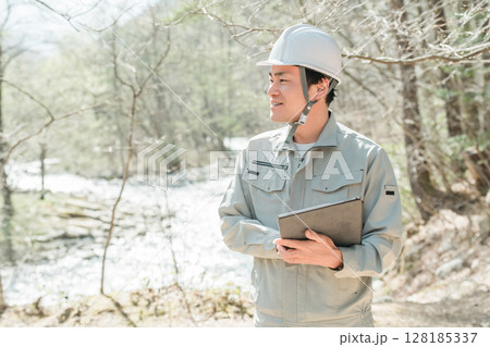 川・河川で河川調査・水質調査をする作業服姿の施工管理技士の男性 128185337