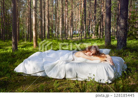 Woman sleeps on a mattress in the summer forest 128185445