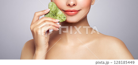 Young woman doing scrapping massage facial skin Young woman doing scrapping massage facial skin 128185449