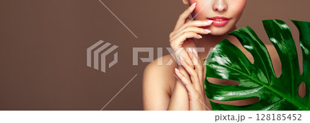 Close up woman face with green exotic leaf Close up woman face with green exotic leaf 128185452