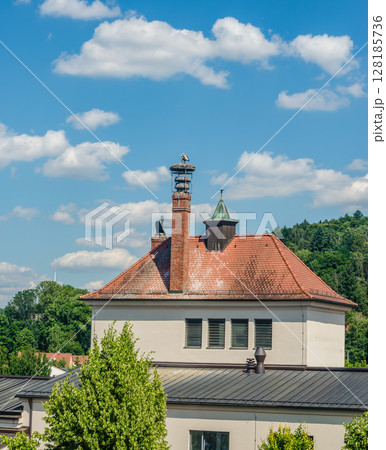 A stork's nest on a chimney of a red-roofed building against a blue sky. High quality photo A stork's nest on a chimney of a red-roofed building against a blue sky. High quality photo 128185736