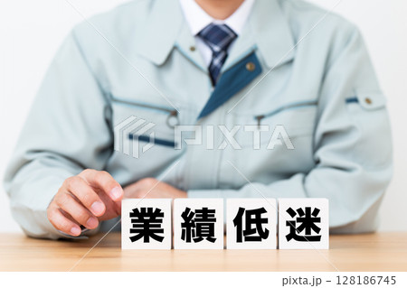 業績低迷のブロックと作業着を着たミドル男性ビジネスマン 業績低迷のブロックと作業着を着たミドル男性ビジネスマン 128186745