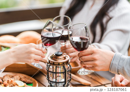 ウッドデッキでホームパーティー・グランピングで乾杯する若い男女グループの手元 128187061