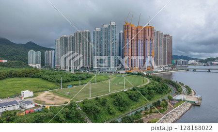 July 1 2025 View of Urban Skyscrapers Beside a Green Park and Riverside Pathway 128188022