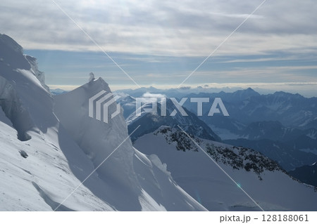 Tranquil Lake With Lush Green Forest, Snow-Capped Mountain, Blue Sky And White Clouds Tranquil Lake With Lush Green Forest, Snow-Capped Mountain, Blue Sky And White Clouds 128188061