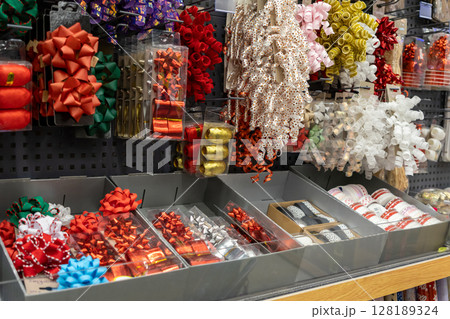 Vibrant gift bows and colorful curling ribbons neatly displayed on retail shelves, offering a festive selection for holiday celebrations and present wrapping 128189324