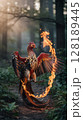 A powerful phoenix, with vibrant fiery plumage, stands amidst a dark forest. 128189445