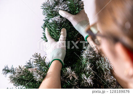 assembling artificial christmas tree branches with gloves, preparing frosted tree for storage or holiday decoration assembling artificial christmas tree branches with gloves, preparing frosted tree for storage or holiday decoration 128189876