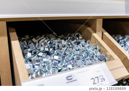 metal nuts in a wooden storage box at a hardware store, close-up view of fastening materials for construction and repair 128189889