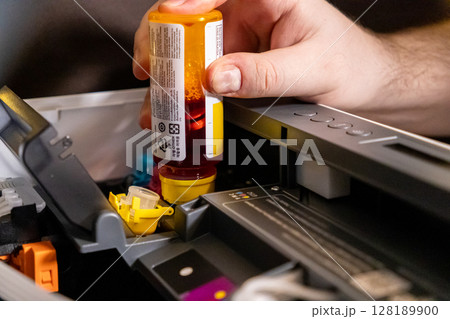 refilling yellow ink tank in printer during maintenance to ensure optimal printing quality 128189900