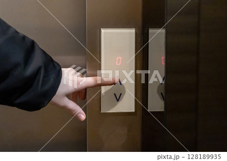 pressing an elevator button with a hand, highlighting interaction with modern technology and vertical transportatio 128189935