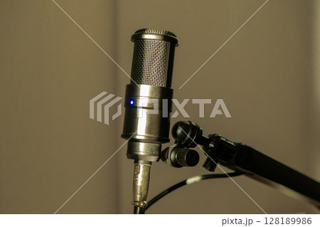 Professional studio microphone on an adjustable stand with warm ambient lighting 128189986
