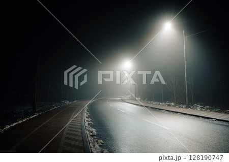 Foggy Road at Night with Headlights and Street Lights 128190747