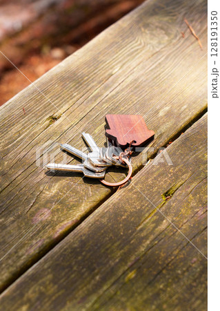 Bunch of keys thrown on wooden antique table with house shaped keychain Bunch of keys thrown on wooden antique table with house shaped keychain 128191350