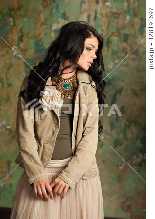 Nice young fashion woman standing against green stucco wall background 128191697