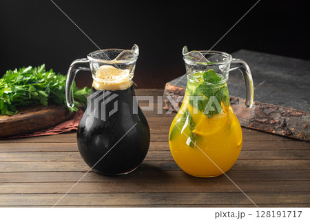 Kvass and lemonade in glass jugs on wooden table 128191717