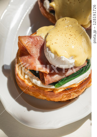 Portion of benedict eggs with sauce and brioche Portion of benedict eggs with sauce and brioche 128191726