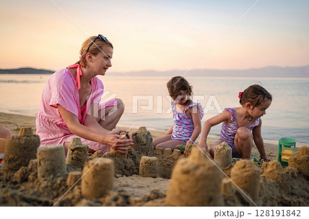 Building sandcastles together at sunset on a beautiful beach Building sandcastles together at sunset on a beautiful beach 128191842