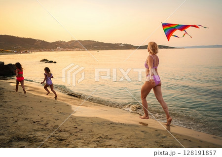 Family shares joyful kite-flying moments at sunset 128191857
