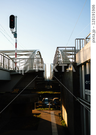 Low angle view capturing railway bridge adorned with red traffic light, while cars sit parked underneath, set against sunny day in Krakow, Poland, showcasing urban architecture. Railway bridge view Low angle view capturing railway bridge adorned with red traffic light, while cars sit parked underneath, set against sunny day in Krakow, Poland, showcasing urban architecture. Railway bridge view 128191986