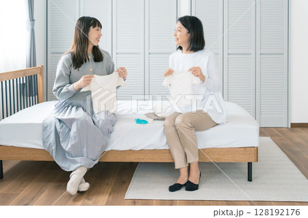 寝室で赤ちゃんの服を準備する母と娘 128192176