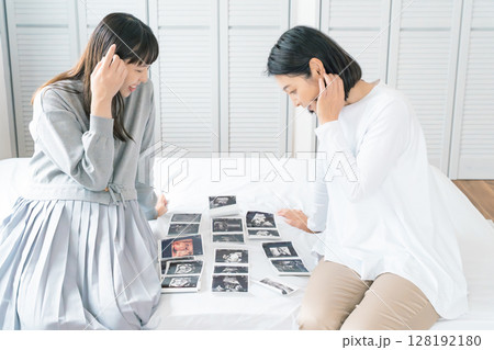 エコー写真を見ながら、赤ちゃんが生まれてくるのが待ち遠しい母と娘 エコー写真を見ながら、赤ちゃんが生まれてくるのが待ち遠しい母と娘 128192180