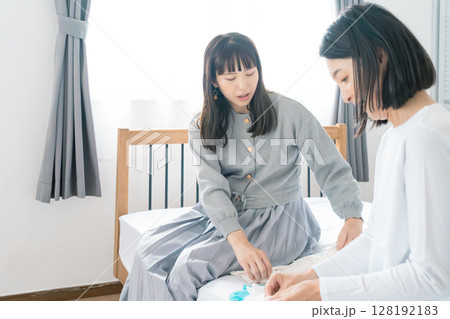 寝室で赤ちゃんの服を準備する母と娘 寝室で赤ちゃんの服を準備する母と娘 128192183