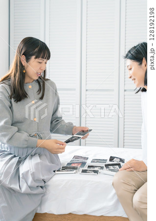 エコー写真を見ながら、赤ちゃんが生まれてくるのが待ち遠しい母と娘 128192198