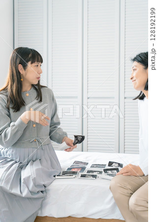 エコー写真を見ながら、赤ちゃんが生まれてくるのが待ち遠しい母と娘 128192199