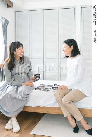 エコー写真を見ながら、赤ちゃんが生まれてくるのが待ち遠しい母と娘 128192200