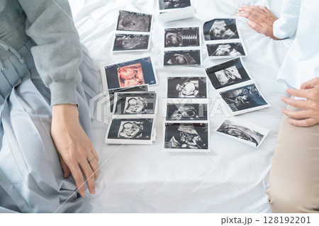 エコー写真を見ながら、赤ちゃんが生まれてくるのが待ち遠しい母と娘 128192201