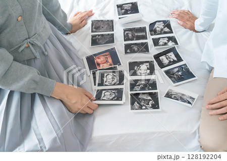エコー写真を見ながら、赤ちゃんが生まれてくるのが待ち遠しい母と娘 128192204