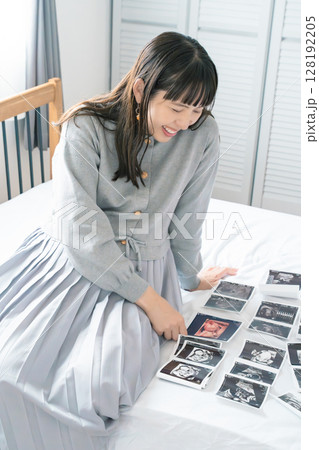 エコー写真を見ながら、赤ちゃんが生まれてくるのが待ち遠しい母と娘 128192205