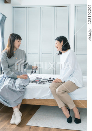 エコー写真を見ながら、赤ちゃんが生まれてくるのが待ち遠しい母と娘 128192206