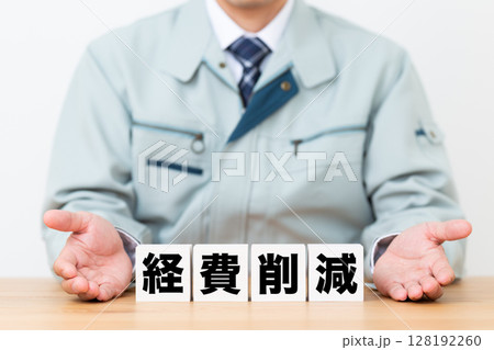 経費削減のブロックと作業着を着たミドル男性ビジネスマン 経費削減のブロックと作業着を着たミドル男性ビジネスマン 128192260