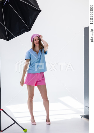 Beautiful girl in pink beret and shorts and light blue t-shirt posing in studio on white background. Vertical photo. High quality photo 128192809