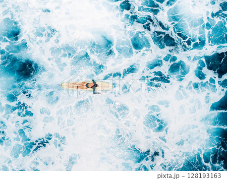 Woman on surfboard in blue ocean with foam waves. Drone view of woman during surfing 128193163