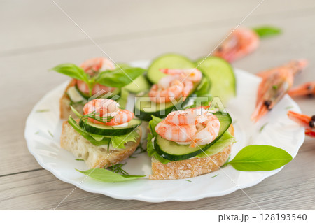 Delicious portioned appetizers with shrimps and greens on a wooden table Delicious portioned appetizers with shrimps and greens on a wooden table 128193540