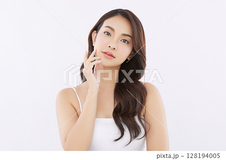 A beautiful young Asian woman with clean, fresh skin against a white background. Skincare, facial treatment, cosmetology, beauty, and spa. An elegant portrait of an Asian woman. 128194005